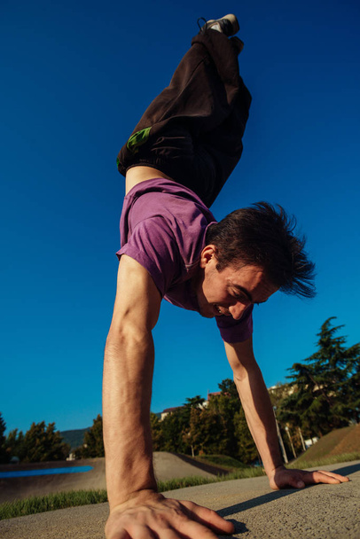 Egy fiatalember, aki a helyi skateparkban gyakorolja a parkour gyakorlatokat egy napsütéses napon. - Fotó, kép