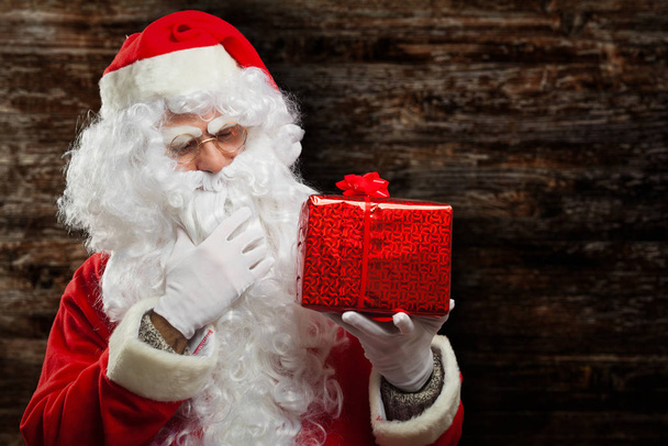 Retrato interior de Papai Noel segurando um presente
 - Foto, Imagem