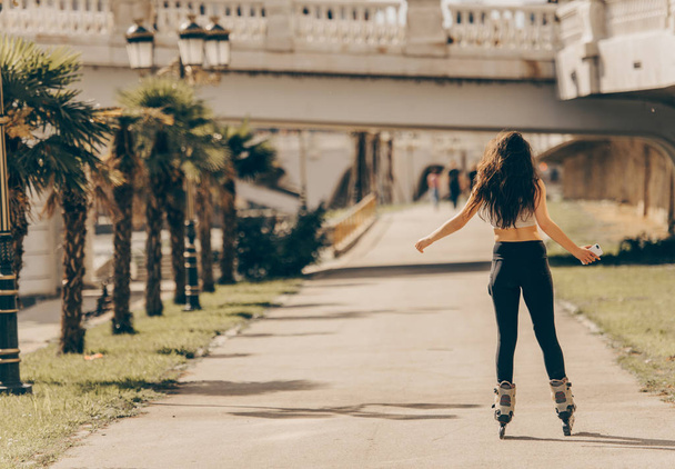 Menina urbana está no parque, olhando feliz enquanto patinação
 - Foto, Imagem