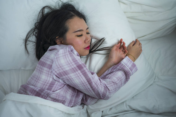 lifestyle portrait of young beautiful and sweet Asian Korean girl on her 20s alone at home sleeping relaxed wearing pajamas lying on bed happy and comfortable resting  - Φωτογραφία, εικόνα