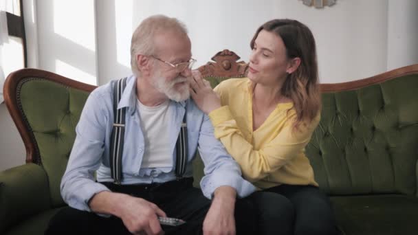 old parents, happy young daughter and loving elderly grandfather have fun cute chatting and laughing while sitting on couch during family weekend - Video, Çekim
