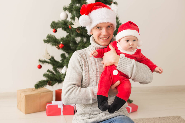 Otec s jeho chlapeček nosí Santa klobouky slaví Vánoce. - Fotografie, Obrázek