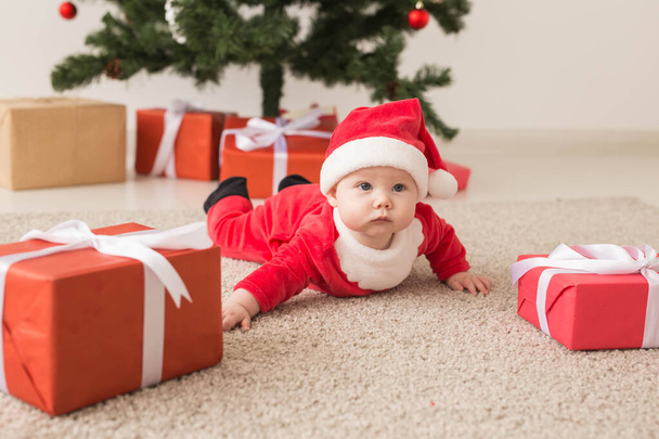 Roztomilá holčička v obleku Santa Clause plazící se po podlaze nad vánočním stromečkem. Dovolená. - Fotografie, Obrázek