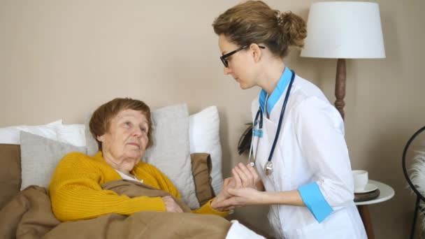 Physician Measures Senior Patients Pulse. Female Nurse Or Doctor Visits Elderly Woman At Home. - Séquence, vidéo