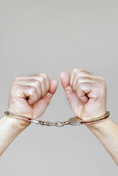 Criminal hands locked in handcuffs. Close-up view - Foto, imagen