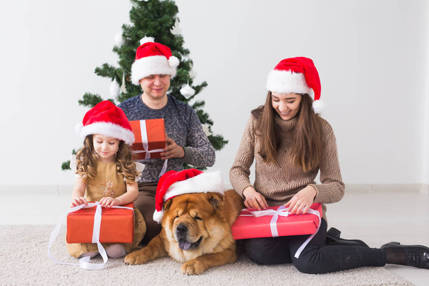 Animaux de compagnie, vacances et concept festif - Famille avec chien sont debout près de l'arbre de Noël
. - Photo, image