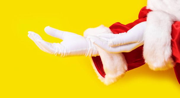 Santa Claus rękawica ręka żółty tło dwa czerwony garnitur przestrzeń skopiować - Zdjęcie, obraz