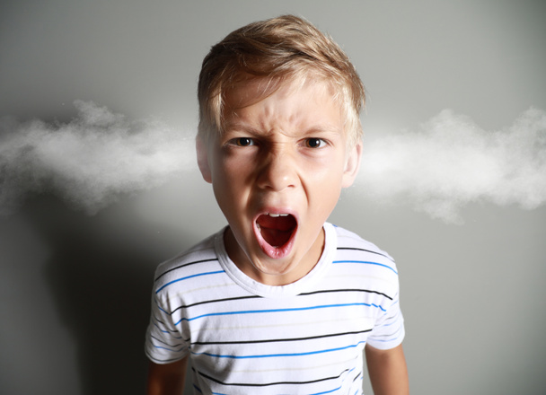 Retrato de niño enojado con vapor saliendo de las orejas sobre fondo gris
 - Foto, Imagen