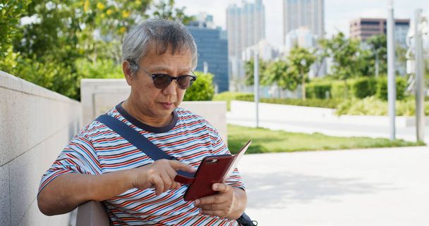 Asiatique vieil homme utilisation de téléphone intelligent à la ville
 - Photo, image
