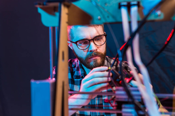 Young male designer engineer using a 3D printer in the laboratory and studying a product prototype, technology and innovation concept - Foto, afbeelding