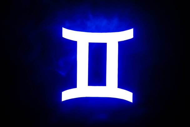 niebieski podświetlany znak zodiaku Gemini z kolorowym dymem na tle - Zdjęcie, obraz