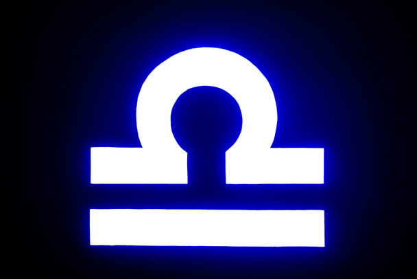 blue illuminated Libra zodiac sign isolated on black - Photo, Image