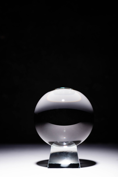 kristallen bol op wit oppervlak op zwarte achtergrond - Foto, afbeelding