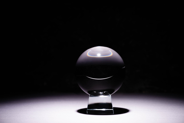 Kristallkugel auf weißer Oberfläche auf schwarzem Hintergrund - Foto, Bild