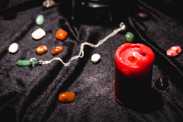 selective focus of fortune telling stones and candle on black velvet cloth - Photo, Image