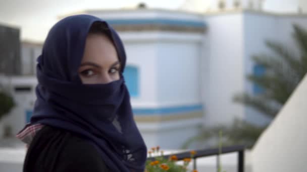 Jonge vrouw in Arabische boerka. Een vrouw kijkt naar de camera. Tegen de achtergrond van het Arabische huis - Video