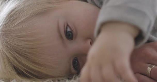 Close-up portrait of extremely beautiful Caucasian baby girl lying on bed. Portrait of calm charming child resting. Cinema 4k ProRes HQ. - Felvétel, videó