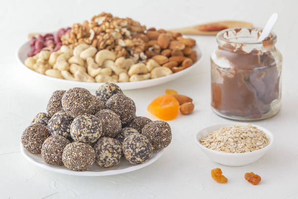 Picaduras naturales saludables de energía cruda, pasta de chocolate y mezcla de frutas secas con nueces en una mesa blanca
 - Foto, imagen