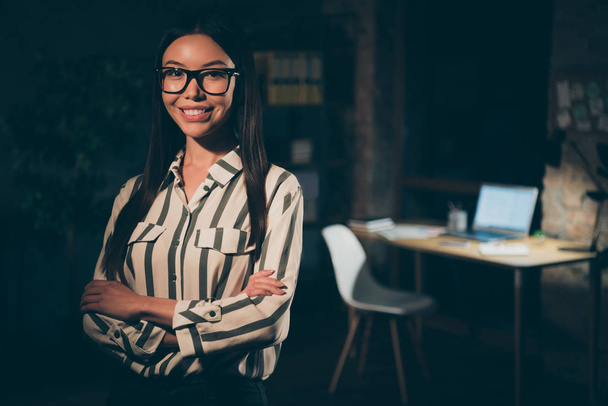 Photo of pretty chinese business lady working late at night meeting foreign colleagues partners crossed arms friendly smiling wear specs striped shirt dark modern office - 写真・画像