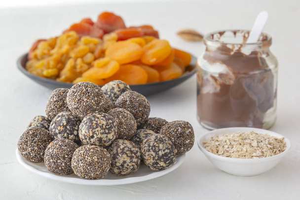 Mordeduras naturales saludables de energía cruda, pasta de chocolate y mezcla de frutas secas con nueces en una mesa blanca. Primer plano
 - Foto, imagen