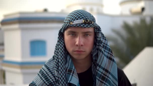 Νεαρός με αραβικό μαντήλι. Ο άνθρωπος καλύπτει το πρόσωπό του. Με φόντο το αραβικό σπίτι. - Πλάνα, βίντεο