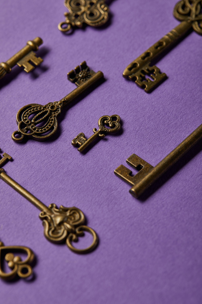 close up view of vintage keys on violet background - Foto, Imagen