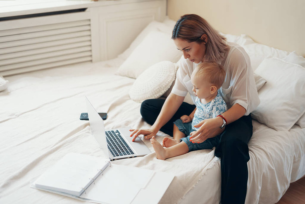 Mujer moderna que trabaja con un niño. Concepto multitarea, freelance y maternidad
 - Foto, Imagen