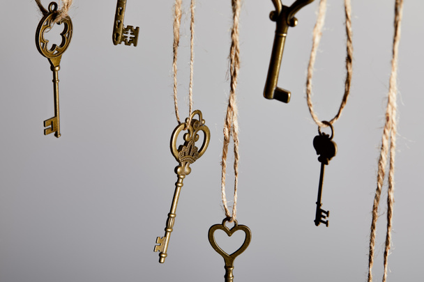 close up view of vintage keys hanging on ropes isolated on grey - Photo, Image