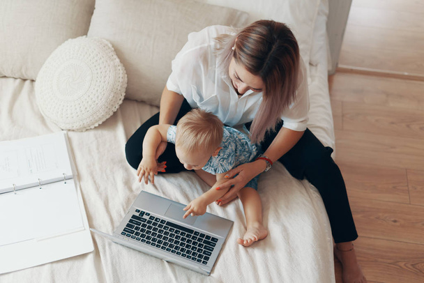 Moderne vrouw die met een kind werkt. Multi-tasking, freelance en moederschap concept - Foto, afbeelding