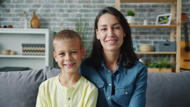 Portrait of happy young family mother and son smiling sitting together indoors - Filmagem, Vídeo
