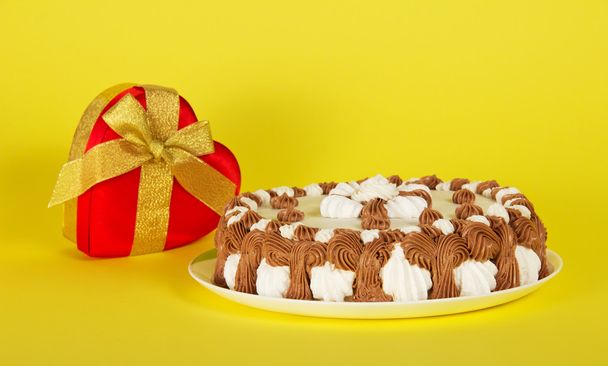 Dish with a pie and a gift a heart on a yellow background - Fotoğraf, Görsel