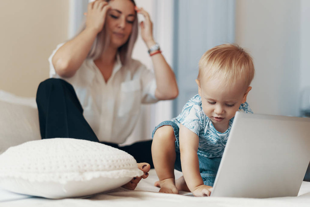 Modern woman working with child. Multi-tasking, freelance and motherhood concept - Photo, Image