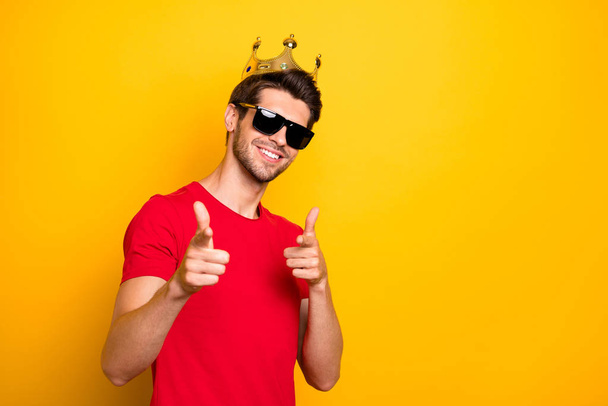 Portrait of cheerful cool guy have gold diadem point index finger in camera choose best team ever wear red t-shirt isolated over bright color background - Fotó, kép