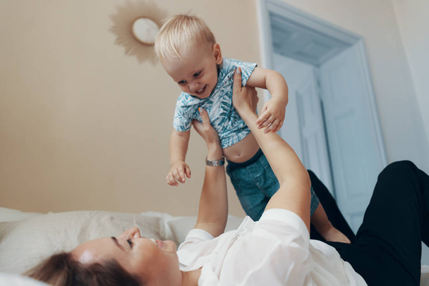 Young mother having fun laughing playing funny active games with cute child son in bedroom - Foto, immagini