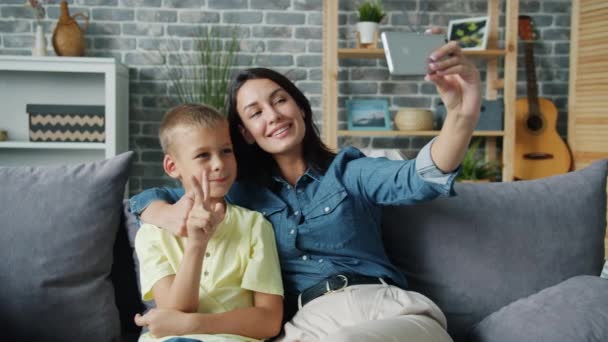 Pretty girl mother taking selfie with cute son smiling gesturing holding smartphone - Footage, Video