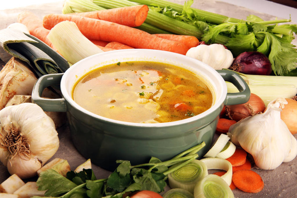 Broth with noodles and carrots, various fresh vegetables in a po - Photo, Image
