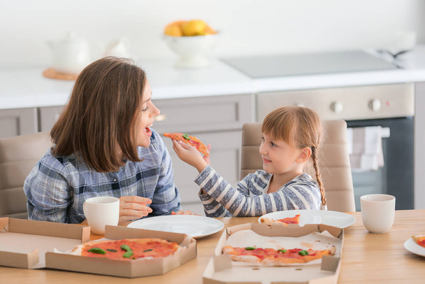 Felice madre e la sua figlioletta mangiare pizza a casa
 - Foto, immagini