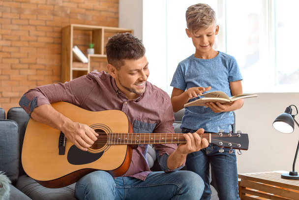 Father and his little son with guitar at home - Photo, Image