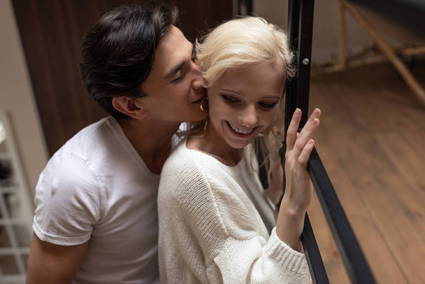 Handsome man whispering to smiling girlfriend at home - Valokuva, kuva