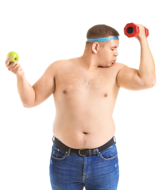 Muž s nadváhou s činkou, měřicí páskou a jablkem na bílém pozadí. Koncept hubnutí - Fotografie, Obrázek