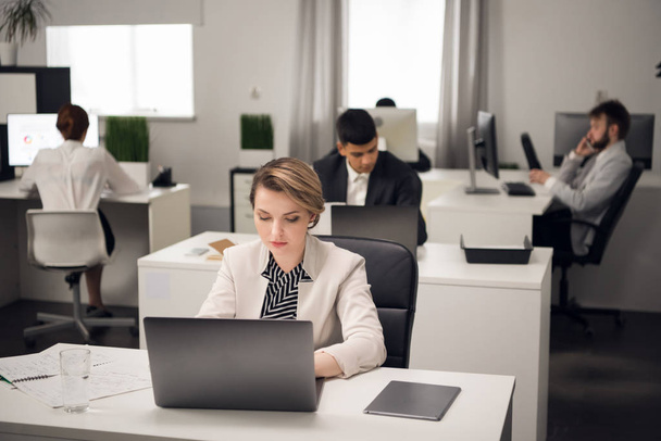 Женщина и ее коллеги сидят за столом с ноутбуком
 - Фото, изображение