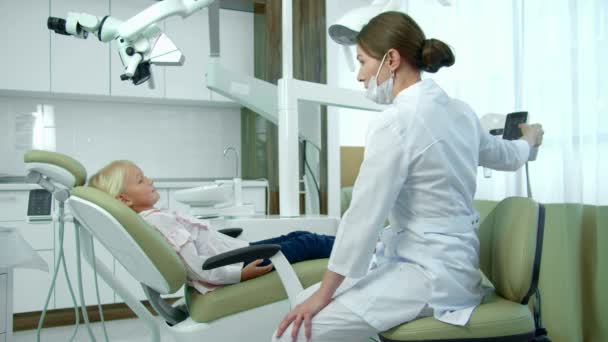 Zahnarzt rückt Stuhl zurück, kleines Mädchen sitzt. - Filmmaterial, Video