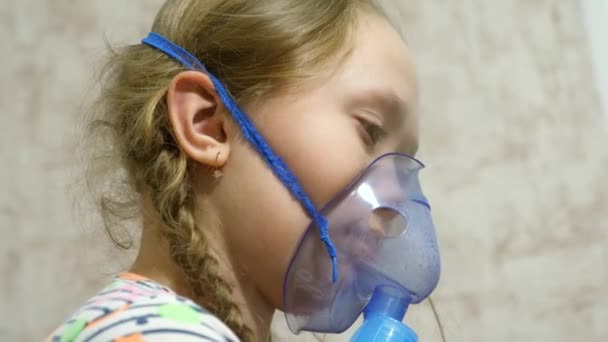 Ein krankes Mädchen behandelt eine Kehle mit einem Inhalator durch einen Hauch von Medizin. Nahaufnahme. Ein Kind in einer Maske inhaliert mit einem Vernebler in die kleinen Blasen. Baby behandelt Grippe durch Einatmen von Dämpfen - Filmmaterial, Video