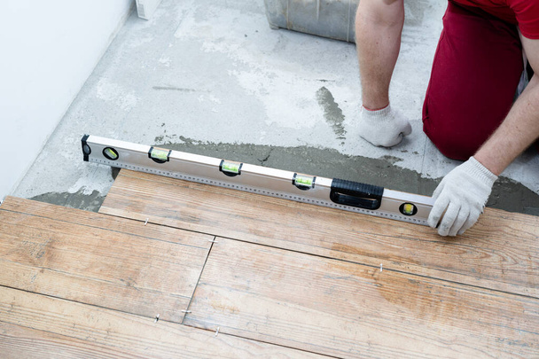 reparatie en decoratie. de tegel zet de porseleinen tegels op de vloer in het appartement - Foto, afbeelding