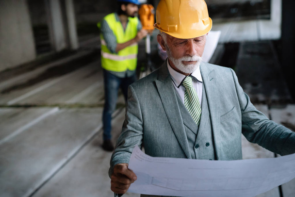 Confident senior construction engineer, architect, businessman working on building site - Fotoğraf, Görsel