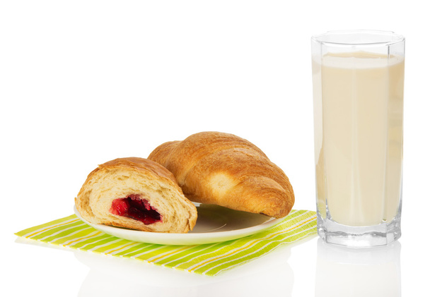 Fresh croissants with jam on a napkin and the milk glass, isolated on white - Fotó, kép