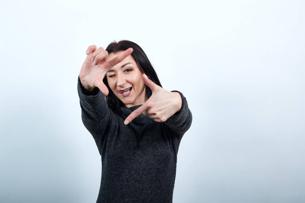 Cheerful woman doing frame gesture at camera, showing tongue - Foto, Bild