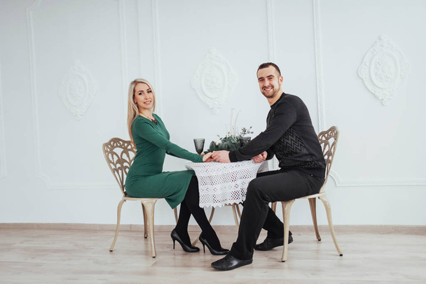 love sitting at the table couple man and woman with wineglasses on white background in the restaurant. valentines dinner. - Zdjęcie, obraz