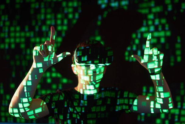 Double exposure of a caucasian man and Virtual reality VR headset is presumably a gamer or a hacker cracking the code into a secure network or server, with lines of code in green - Fotografie, Obrázek