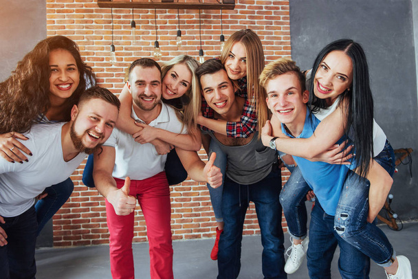 Group portrait of multi-ethnic boys and girls with colorful fashionable clothes holding friend and posing on a brick wall, Urban style people having fun, Concepts about youth and togetherness lifestyle. - Photo, Image